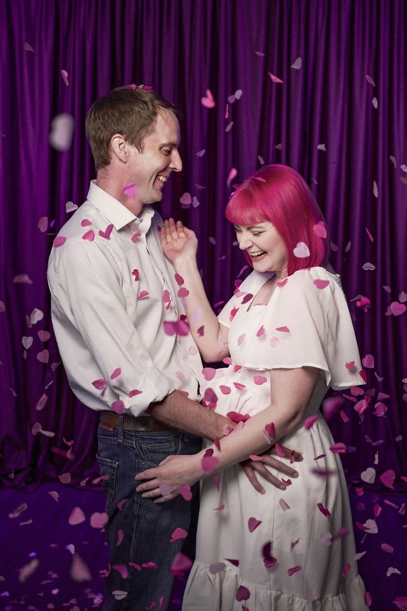 Nirvana and Nick laughing together under a shower of pink paper hearts